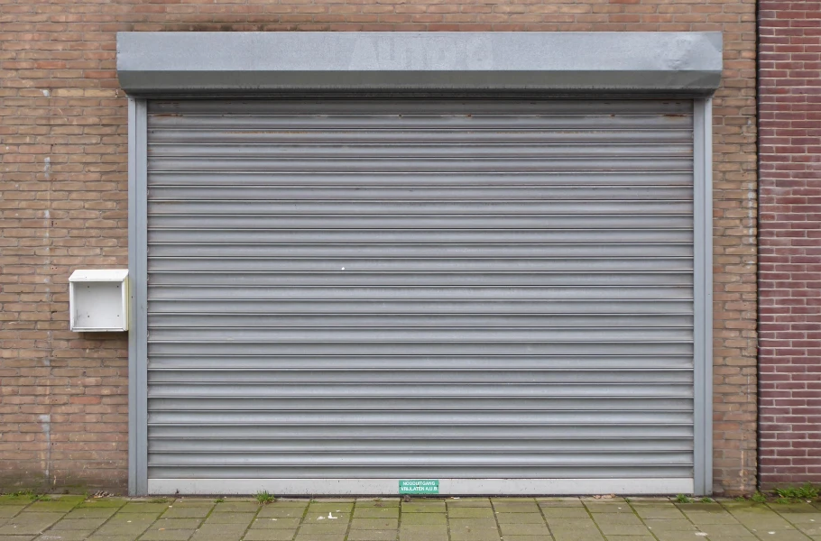 Closed gray metal rolling shutter at a commercial building entrance