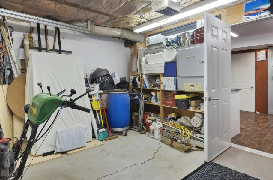 Cluttered residential garage with tools and stored belongings