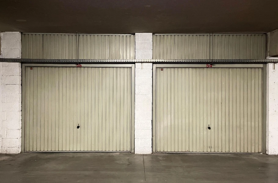 Two closed garage doors viewed from inside an empty warehouse