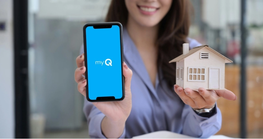 woman holding a phone with the myQ logo and a miniature house